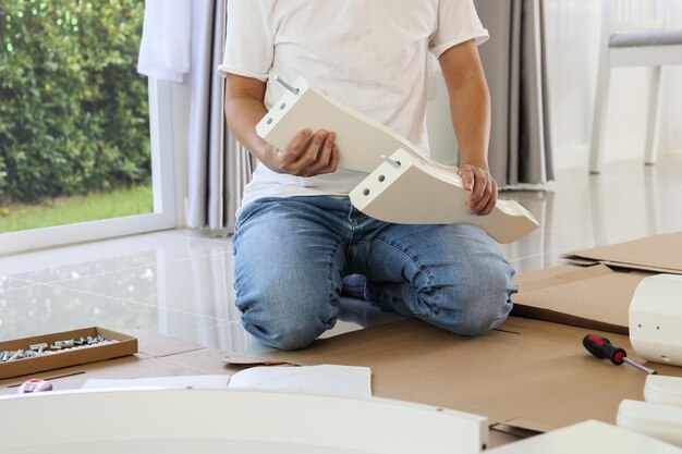 Mężczyzna montujący białe meble stołowe w domu