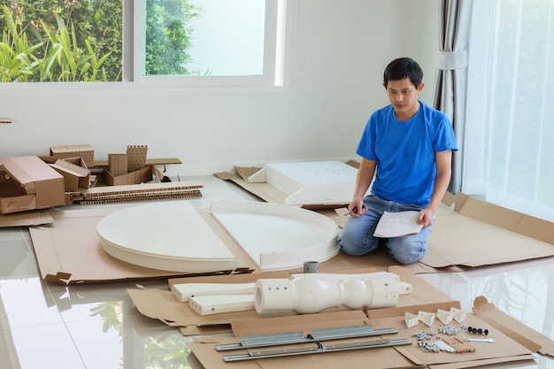 Mężczyzna montujący białe okrągłe meble stołowe w domu