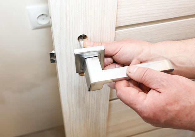 Mężczyzna montuje klamkę do drzwi Prace remontowe Konserwacja w mieszkaniu