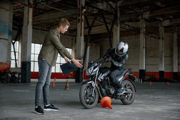 Mężczyzna motocyklista popełnia błąd dotykając stożka podczas zajęcia z jazdy