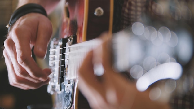 Mężczyzna muzyk gra na gitarze, ręce z bliska, skupienie się na gryfie gitary, koncepcja sztuki