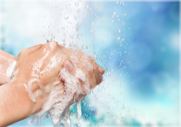 Mężczyzna myje ręce w czystej wodzie na niebieskim tle