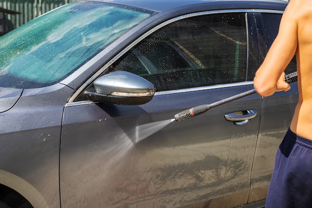 Mężczyzna myje samochód na ulicy