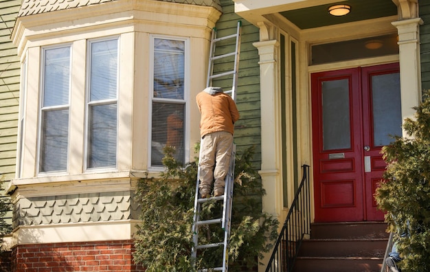 Zdjęcie mężczyzna na drabinie wspina się po domu.