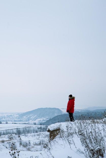 Mężczyzna na klifie z pięknym widokiem na zimowy krajobraz