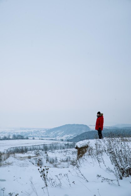 Mężczyzna na klifie z pięknym widokiem na zimowy krajobraz