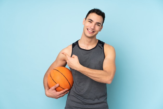 Mężczyzna na niebieską ścianą, grając w koszykówkę i wskazując na boczne