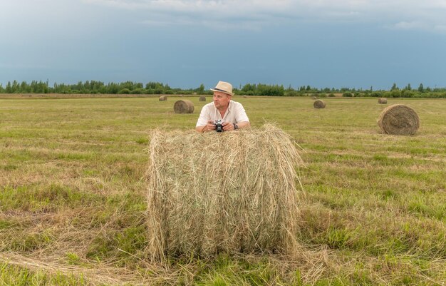 Mężczyzna na polu z belą siana w tle