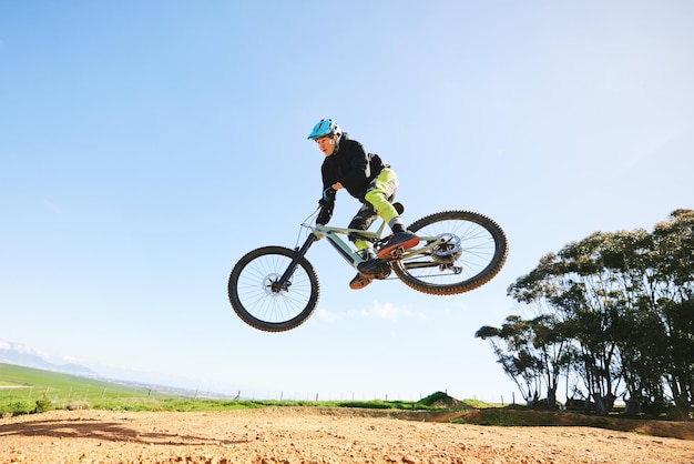 Mężczyzna na rowerze górskim i skok w błękitne niebo, aby uzyskać wydajność kaskaderską i prędkość na makiecie, sportowiec rowerowy i odwaga w powietrzu za ryzyko wolności lub wyścig w zawodach kolarskich z mocą