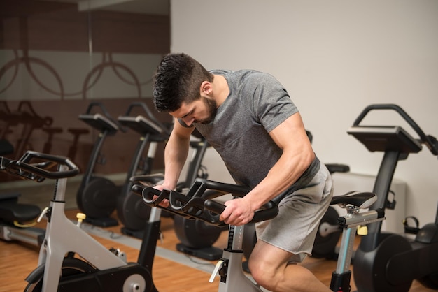 Mężczyzna na siłowni ćwiczący nogi podczas treningu cardio na rowerze