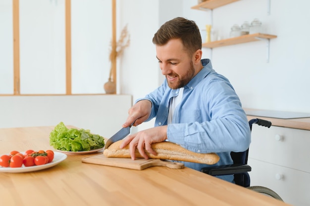 Mężczyzna na wózku inwalidzkim kroi warzywa w kuchni