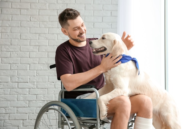 Mężczyzna na wózku inwalidzkim z psem-przewodnikiem w pomieszczeniu