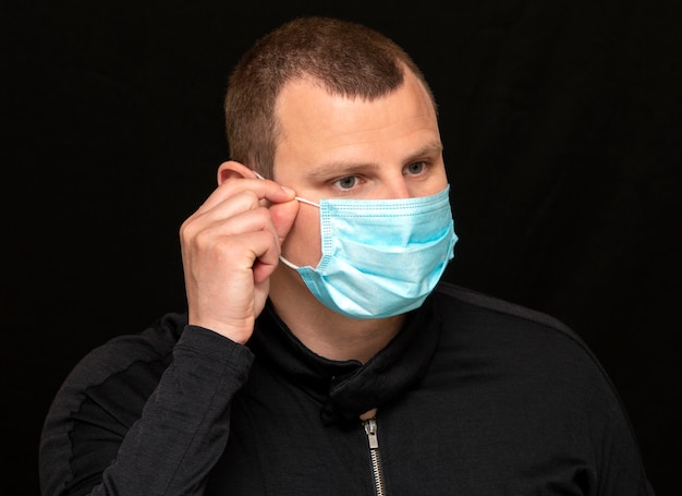 Mężczyzna nakłada na twarz maskę medyczną, instrukcje, jak nosić maskę