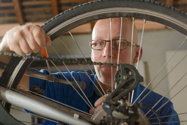 Mężczyzna naprawia bicykl w jego warsztacie.