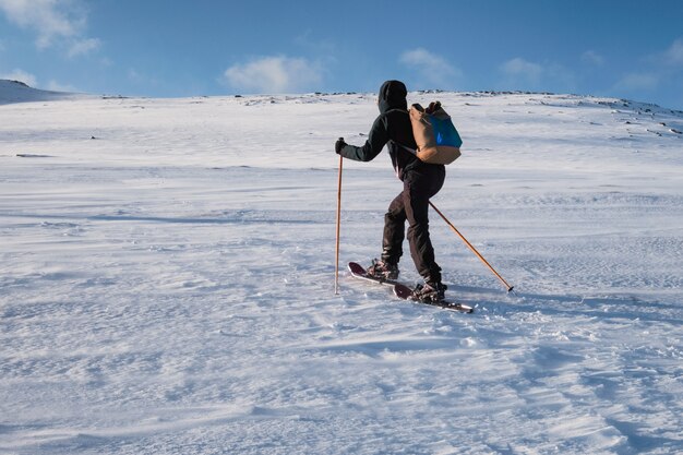 Mężczyzna narciarz z kijki trekkingowe wspinaczka na zaśnieżonym wzgórzu