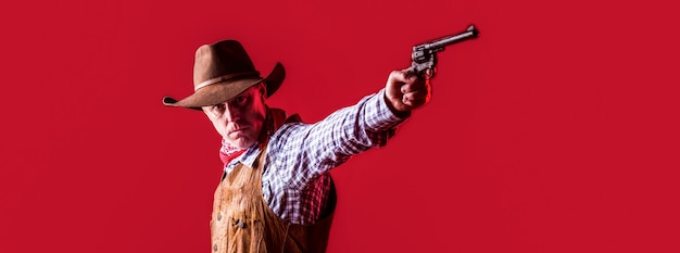 Mężczyzna Nosi Kowbojski Kapelusz, Pistolet. Zachód, Broń. Portret Kowboja. Owboy Z Bronią Na Czerwonym Tle.