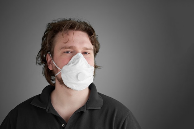 mężczyzna nosi ochronny respirator medyczny. Koncepcja pandemii wirusa. Szare tło