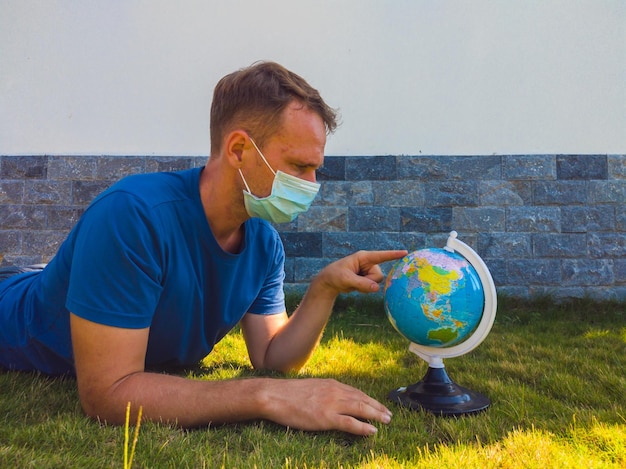 Mężczyzna noszący maskę trzymającą w ręku mapę świata kuli ziemskiej Poddaj się kwarantannie, aby chronić rozprzestrzeniającego się wirusa Kiedy możesz znowu podróżować Epidemia pandemiczna koronawirus 2019ncov sars covid19 koncepcja wirusa