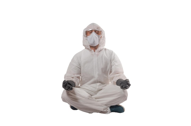 Mężczyzna noszący okulary ochronne i maskę do walki z wirusem Covid19 Corona, siedzący w pozycji jogi i medytujący izolowany nad białym