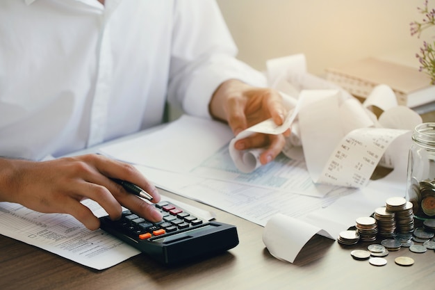 Mężczyzna oblicza rachunki domowe w domu Mężczyzna za pomocą kalkulatora sprawdzającego saldo i koszty w biurze