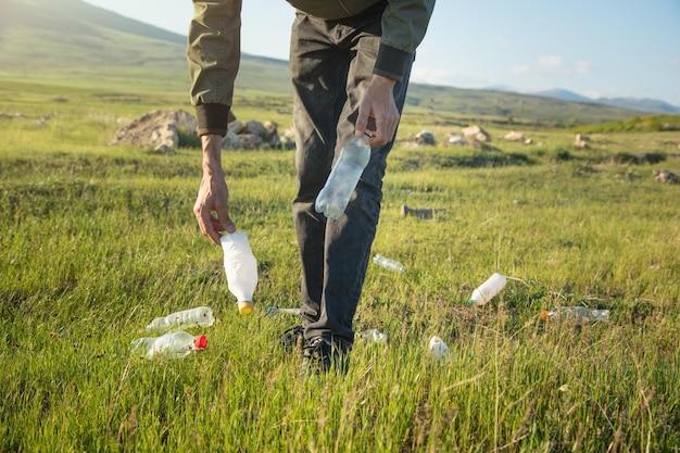 Mężczyzna odbiera plastikowe butelki z parku trawiastego