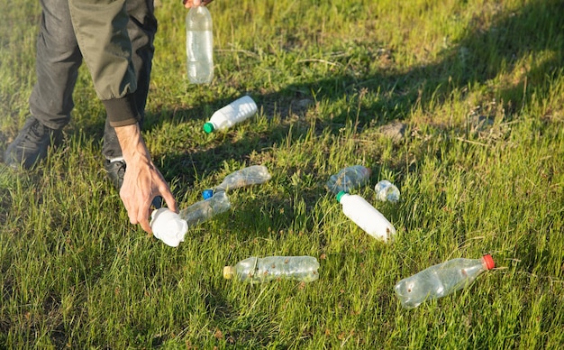 Mężczyzna odbiera plastikowe butelki z parku trawiastego