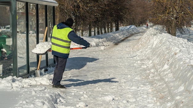 Mężczyzna odgarnia śnieg z chodnika.