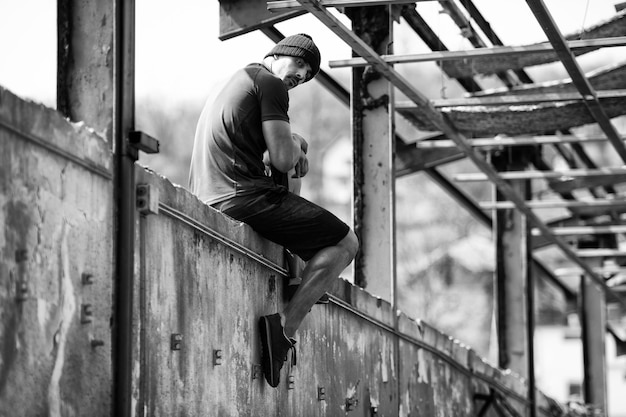 Mężczyzna odpoczywa po ćwiczeniach w magazynie na betonowym bloku