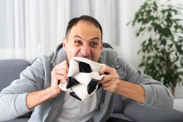 Mężczyzna ogląda piłkę nożną w domu siedząc na kanapie. Wysokiej jakości zdjęcie
