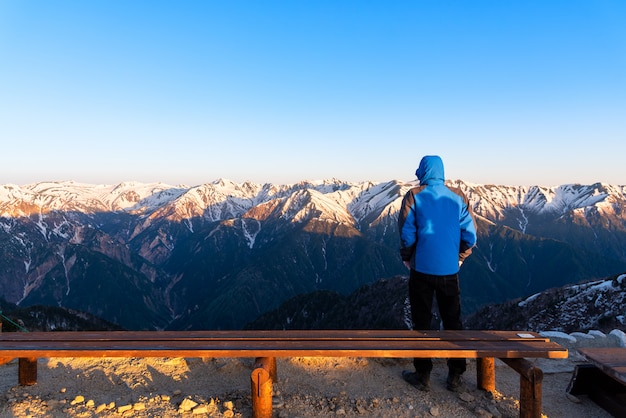 Mężczyzna ogląda scenerię Mount Tsubakuro Dake o zachodzie słońca. Śnieżny pasmo górskie Norther Japonia Alps Chubu-Sangaku park.