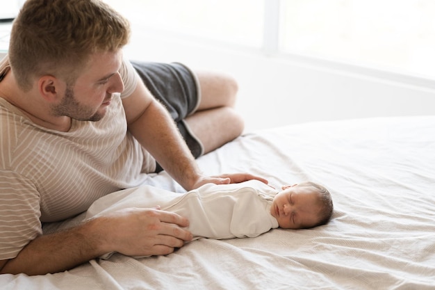 Mężczyzna ojciec leżący z dzieckiem kaukaski włochaty brunet ładny noworodek śpi jeden lub dwa tygodnie dziecko na łóżku krytyCareloveszczęście koncepcja kopiować miejsce