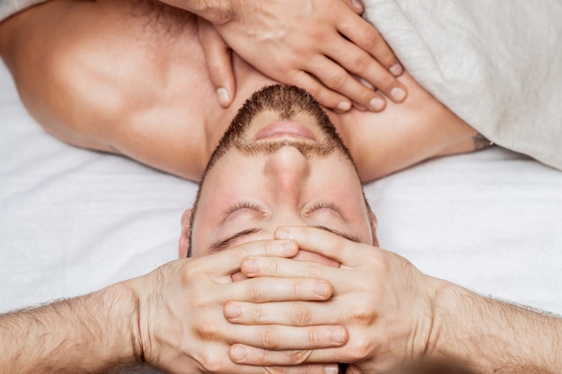 Mężczyzna otrzymujący relaksujący masaż głowy.