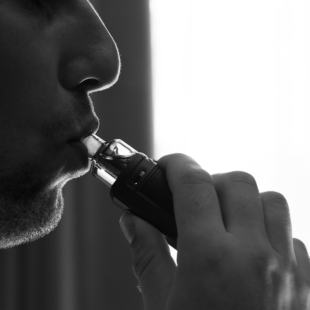 Mężczyzna palący elektroniczny dym papierosowy i zbliżenie warg