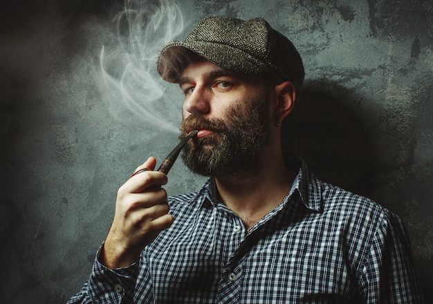Mężczyzna pali fajkę stojącą przy ścianie