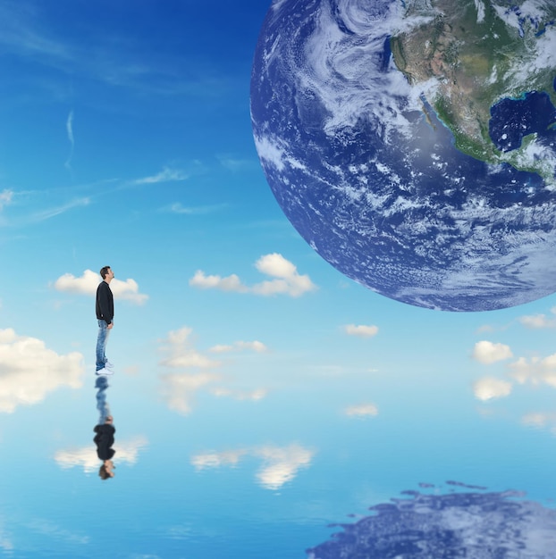 Zdjęcie mężczyzna patrzący na planetę ziemię na niebieskim tle elementy tego obrazu dostarczone przez nasa