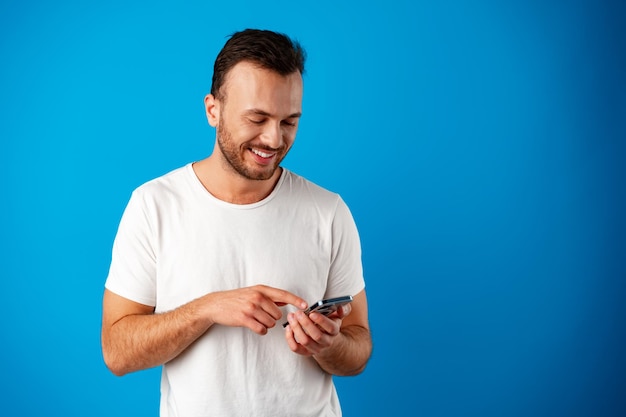 Mężczyzna patrzący na telefon stojący na białym tle na niebieskim tle