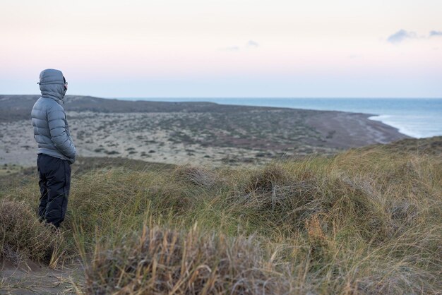 Mężczyzna patrzy na różowy wschód słońca na plaży patagonii