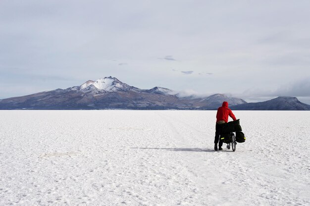 Mężczyzna pcha rower podróżny przez pustynię Uyuni