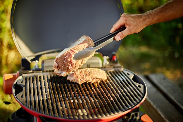 Mężczyzna pieczone mięso na grillu gazowym na grillu na świeżym powietrzu na podwórku