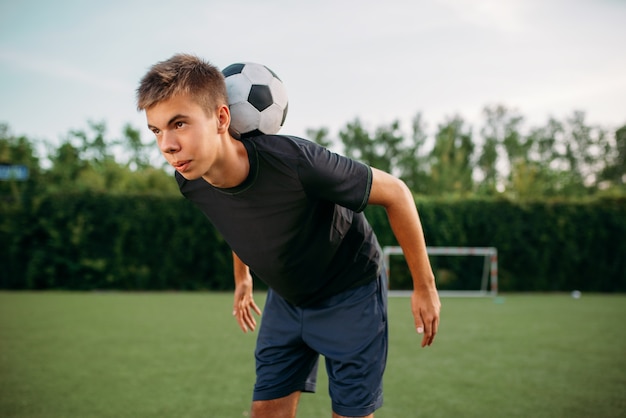 Mężczyzna Piłkarz Utrzymuje Równowagę Z Piłką Na Szyi Na Boisku. Piłkarze Na Stadionie Zewnętrznym, Trening Drużynowy Przed Meczem