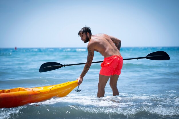 Mężczyzna pływający kajakiem po plaży podczas letnich wakacji