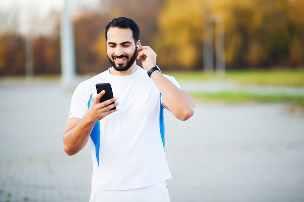 Mężczyzna po treningu w parku miejskim i korzystaniu z telefonu komórkowego