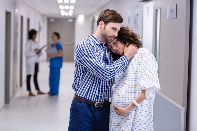 Mężczyzna pociesza kobieta w ciąży w korytarzu