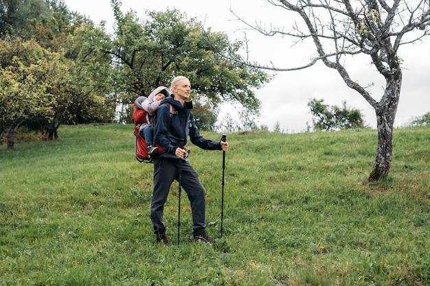 Mężczyzna podróżnik niesie dziecko w plecaku, ojciec zabrał dziecko w góry