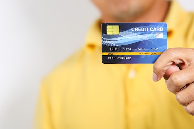 Mężczyzna pokazujący kartę kredytową na białym tle