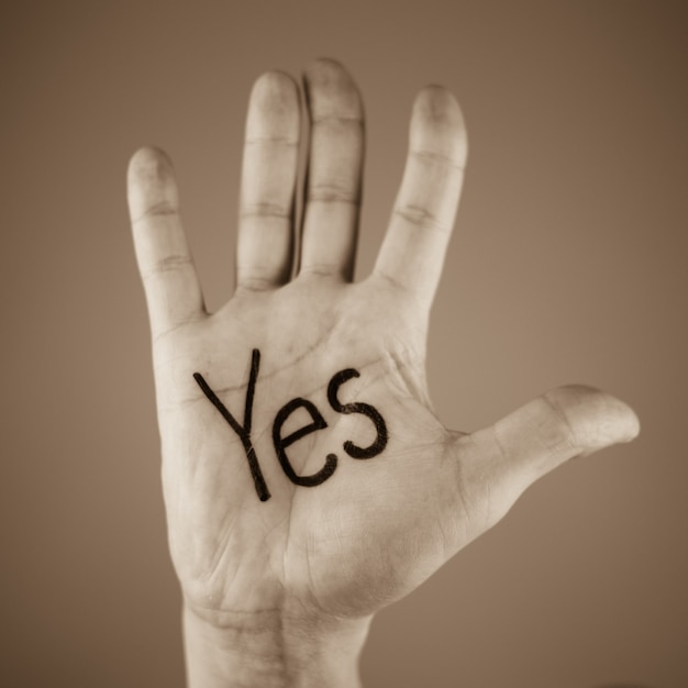 Mężczyzna pokazujący słowo „tak” wypisane na dłoni
