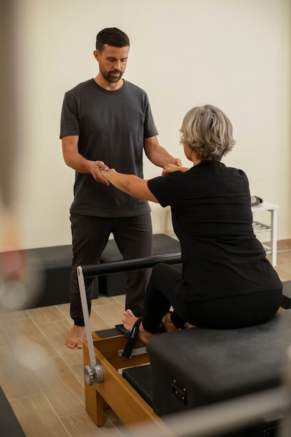 Zdjęcie mężczyzna pomagający kobiecie na zajęciach pilates