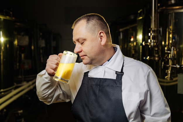 Zdjęcie mężczyzna popijający wysoką szklankę piwa. płytka głębia ostrości z ostrym naciskiem na wargę i piwo.