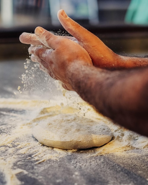 Mężczyzna posypujący mąką ciasto na pizzę