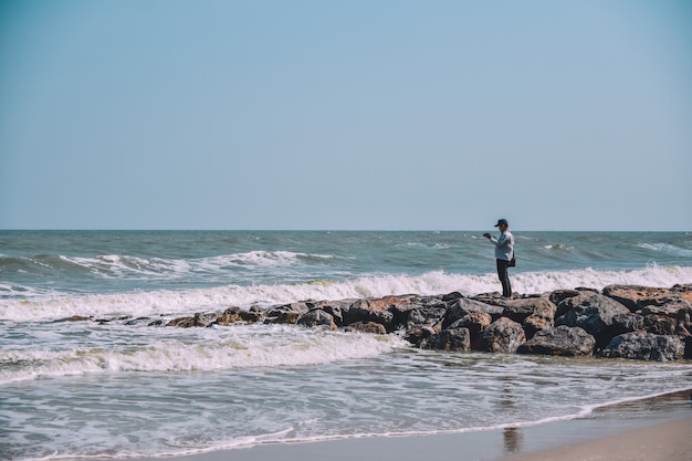 Mężczyzna pozycja na rockowym widoku na plaży i morzu